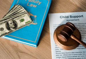 child support agreement documents, dollar bills, gavel, and family law book on top of a table
